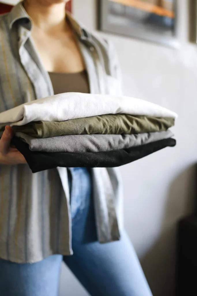 Hands holding a stack of neatly folded shirts