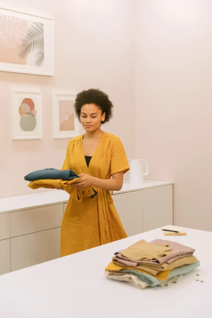 Woman in a yellow dress holding neatly folded clothes