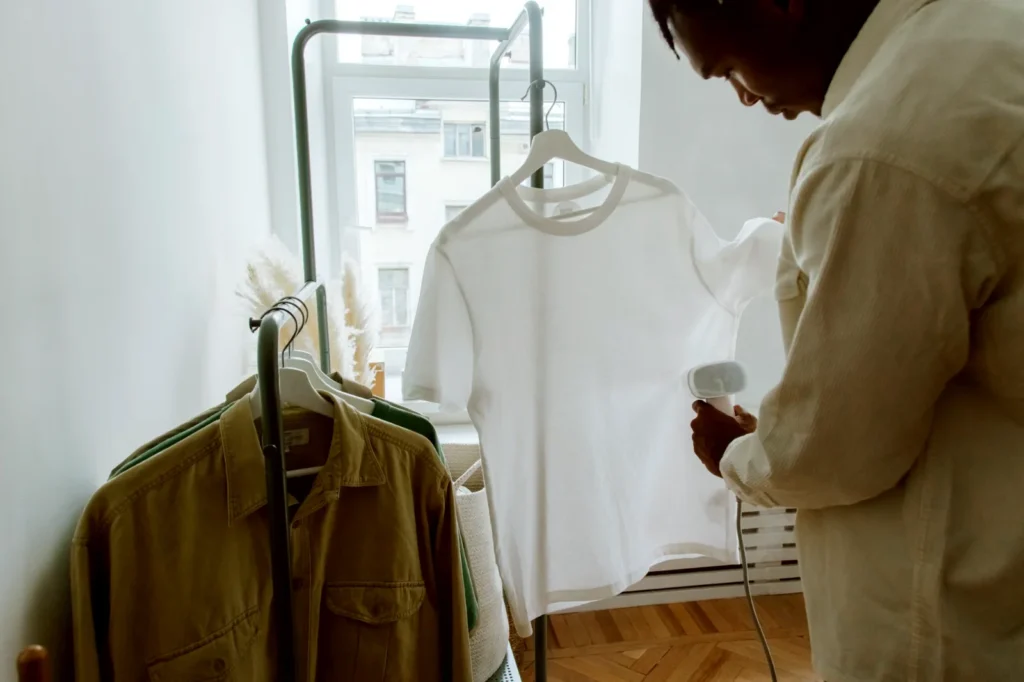 Man steaming a white shirt on a clothing rail