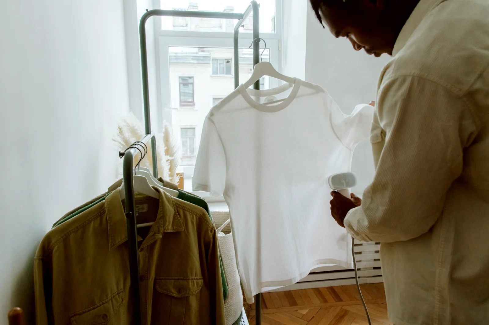 A man steaming a shirt hanging on a rail